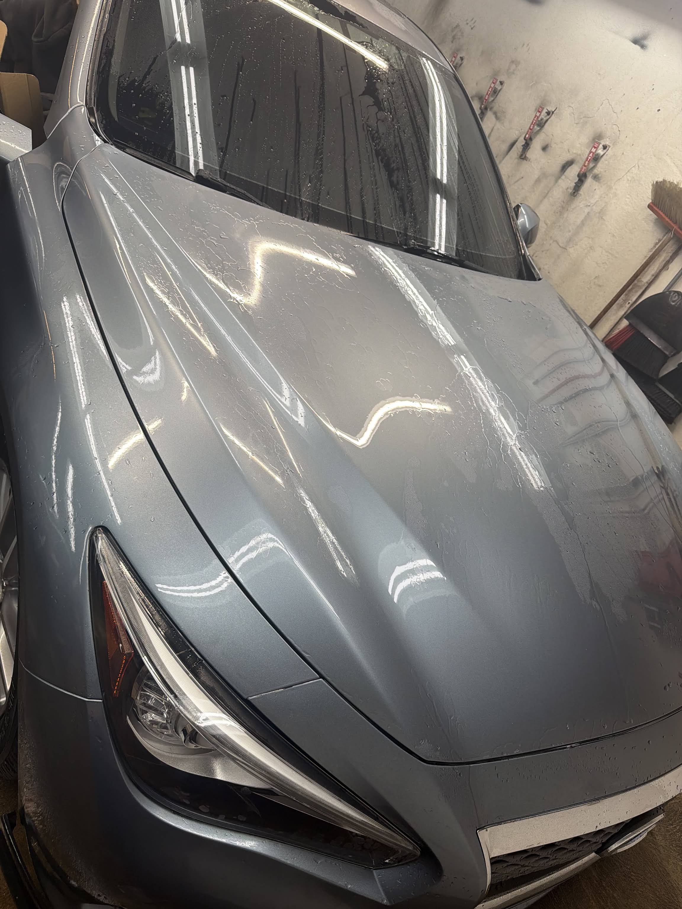 A freshly washed gray hood beading water under shop lights — real work from Full Throttle Details